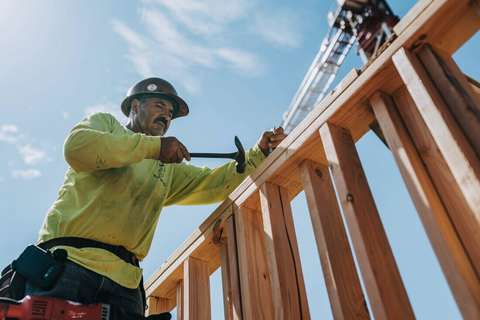 Obrero de la construcción con casco martillando una estructura