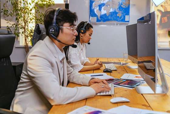 Operadores con auriculares trabajando en un escritorio largo