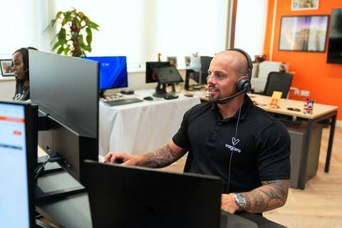 Hombre con auriculares atendiendo frente a la computadora