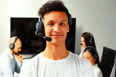 Hombre joven sonriendo con auriculares en un centro de atención