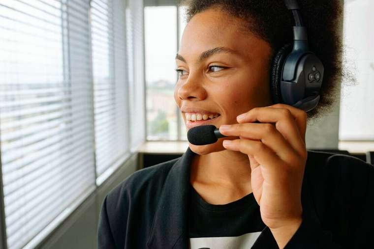 Mujer sonriendo con auriculares sosteniendo el micrófono