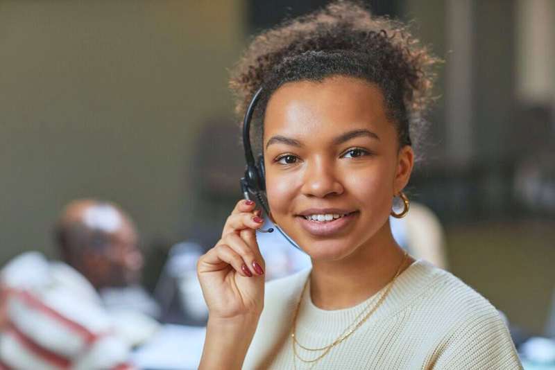 Mujer sonriendo con auriculares en una oficina