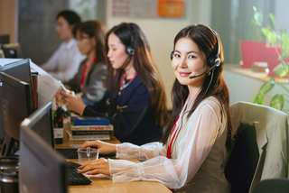 Mujer sonriendo con auriculares frente a la computadora