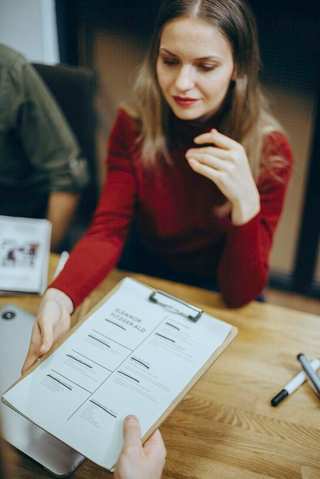 Mujer recibiendo un CV impreso en una tablilla durante una entrevista