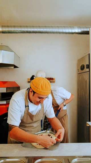 Ayudante de cocina con gorro amarillo y delantal trabajando una masa