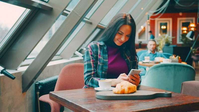 Mujer mirando el celular en un café luminoso