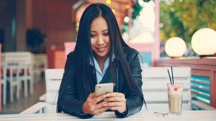 Mujer joven sonriendo mientras mira el celular