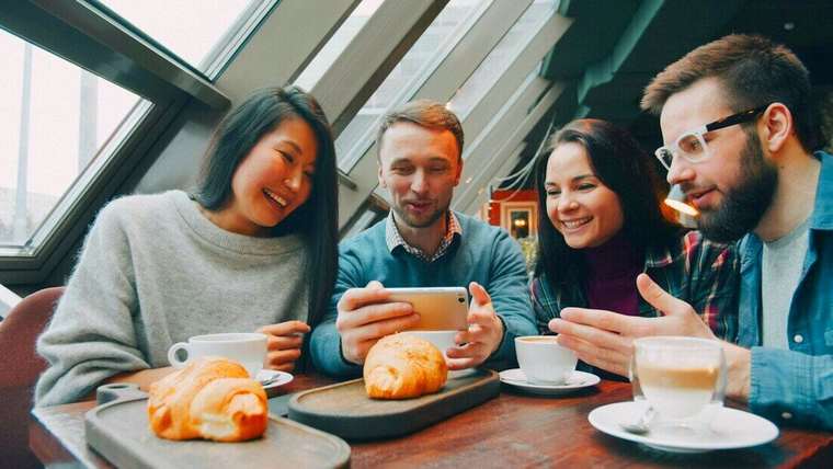 Amigos riendo mientras miran un celular en un café