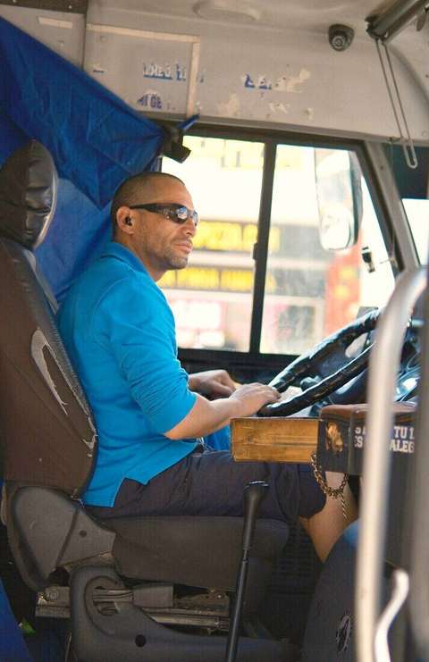Conductor con camisa azul en el asiento de un colectivo