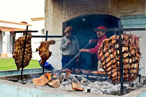 Dos parrilleros cocinando un asado a la estaca al aire libre