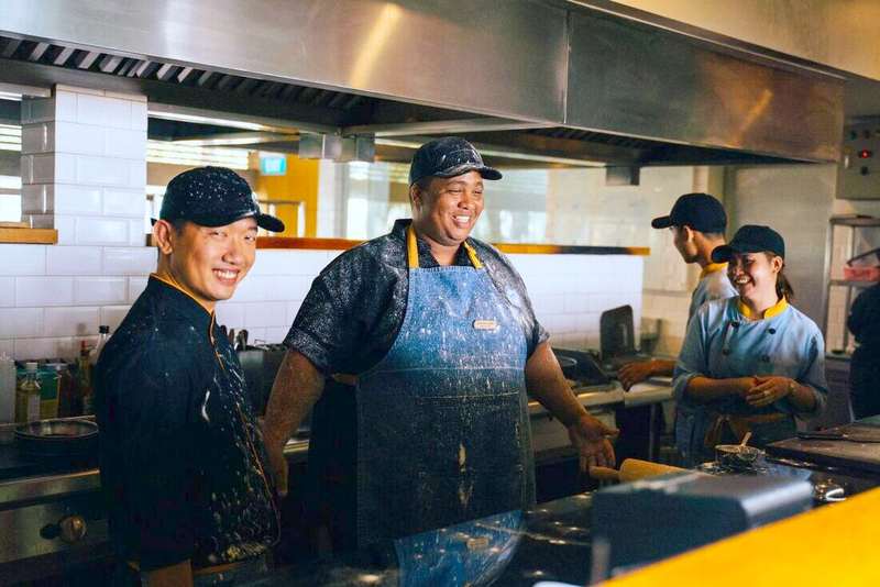 Equipo de cocina riendo detrás de la plancha de un restaurante