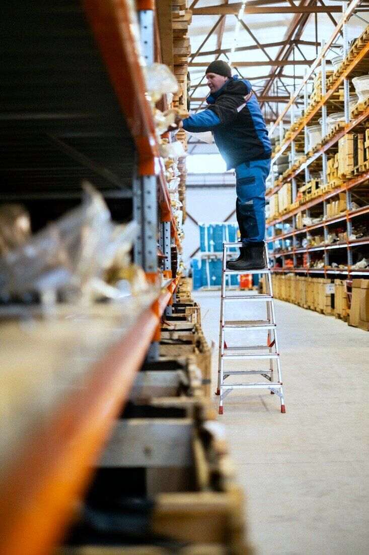 Empleado subido a una escalera en un depósito