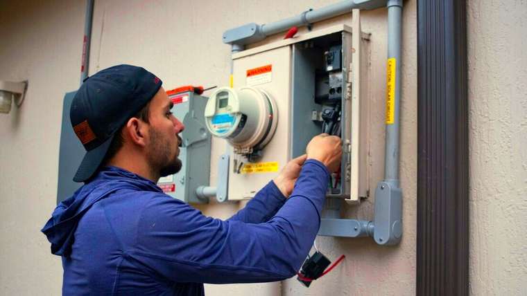 Electricista con gorra trabajando en un tablero de medidor