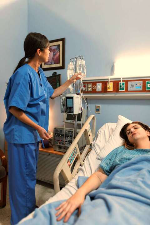 Enfermera controlando un suero junto a la cama de una paciente