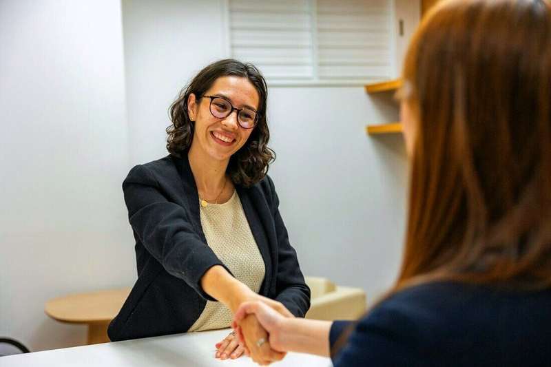 Mujer sonriendo mientras saluda con un apretón de manos