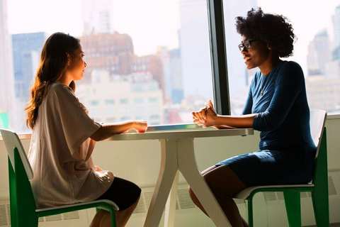 Dos mujeres conversando junto a una ventana