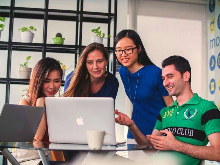 Cuatro estudiantes mirando juntos una notebook
