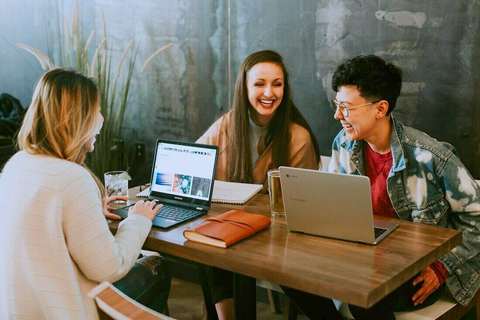 Estudiantes riendo alrededor de una mesa con notebooks