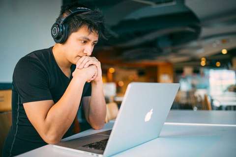 Joven con auriculares frente a una notebook