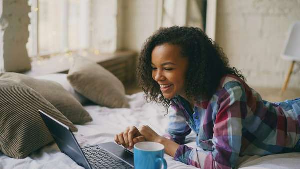Mujer joven riendo frente a su notebook