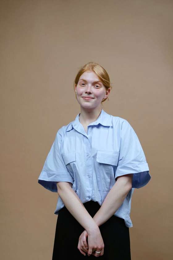 Mujer con camisa celeste frente a un fondo liso beige