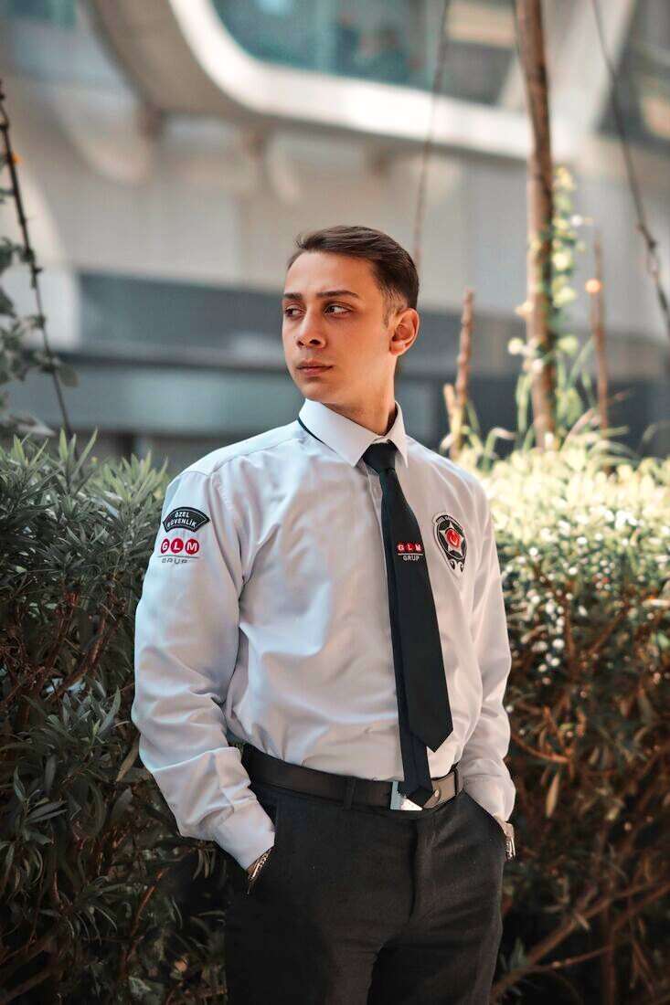 Guardia de seguridad con camisa blanca y corbata negra mirando hacia un costado