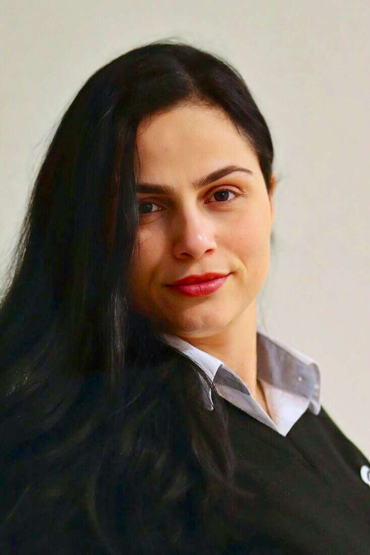 Guardia de seguridad mujer con suéter negro y camisa gris, retrato