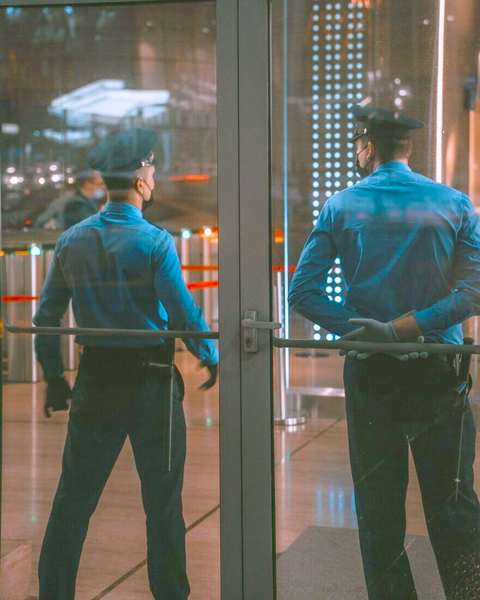 Dos guardias de seguridad de espaldas junto a una puerta de vidrio