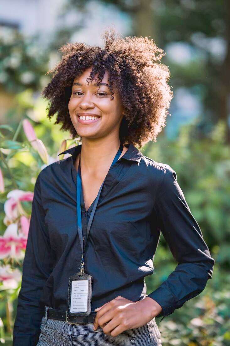 Mujer sonriendo con camisa negra y un cordón con credencial colgado del cuello