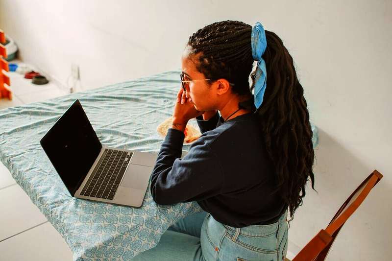 Mujer con trenzas mirando su notebook sobre una mesa
