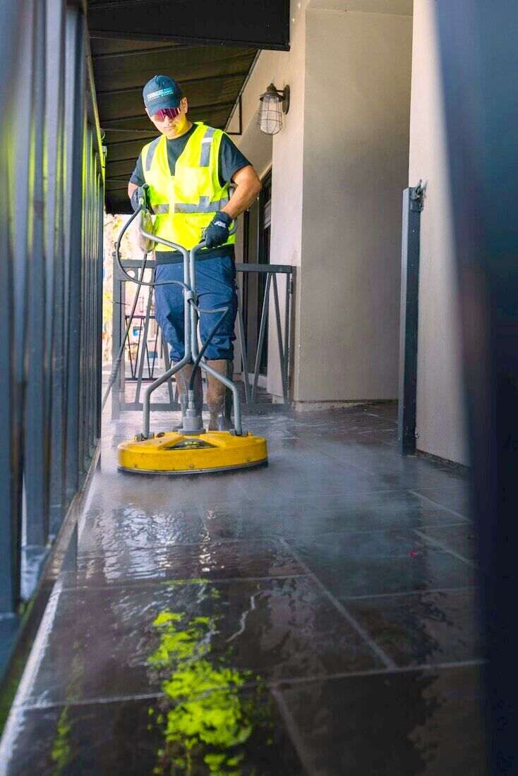 Operario con chaleco amarillo limpiando un piso