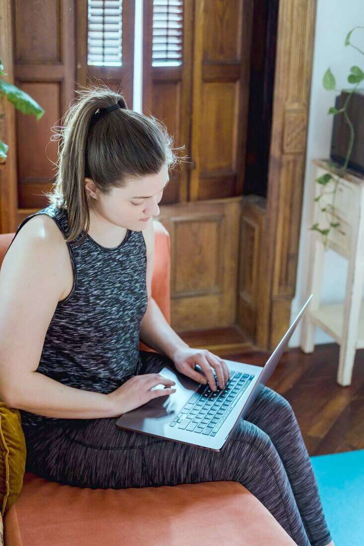 Mujer sentada en un sillón con una notebook sobre las piernas