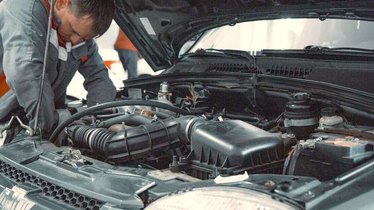 Mecánico revisando el motor de un auto con el capot abierto