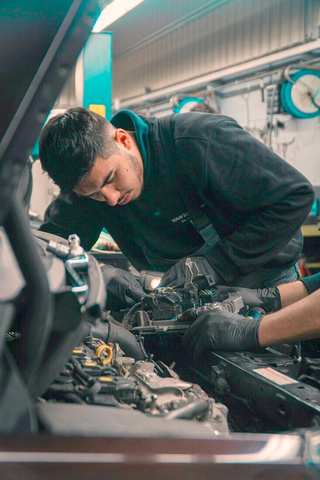 Mecánico trabajando en el motor de un auto en un taller