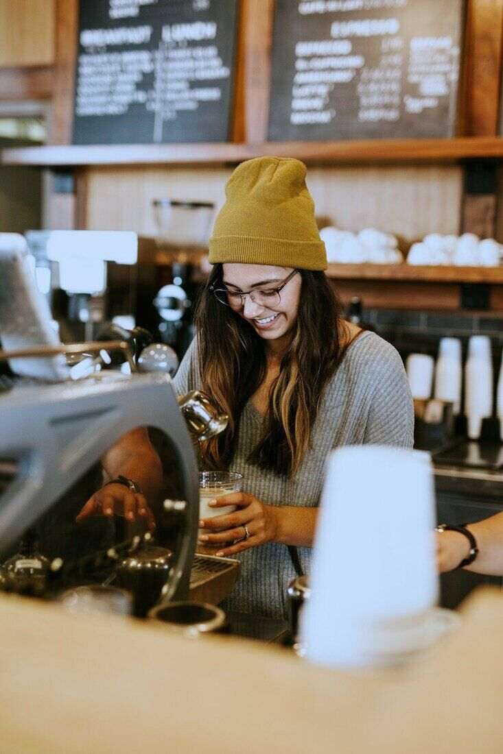 Mujer con gorro de lana y delantal preparando café