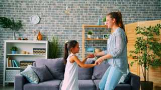 Mujer jugando con una nena en el living de una casa