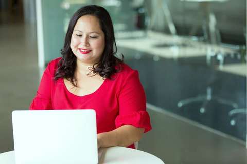 Mujer con blusa roja trabajando en una notebook