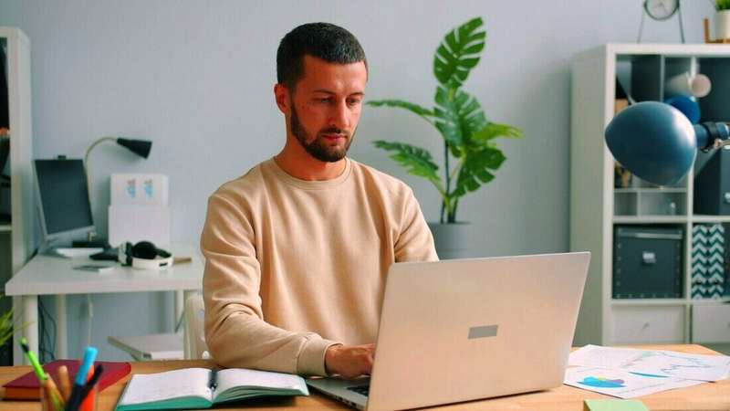 Hombre trabajando con una notebook en un escritorio con plantas