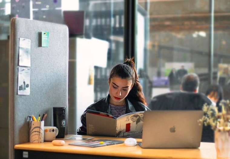 Mujer leyendo junto a su notebook en una oficina