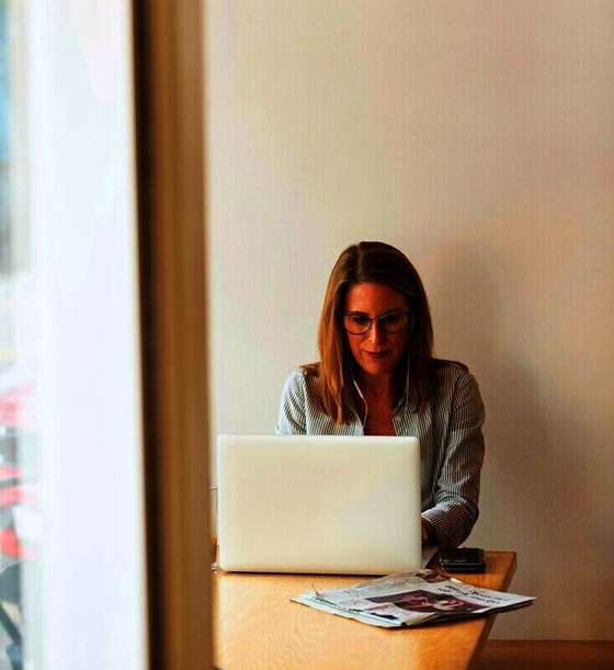 Mujer trabajando con una notebook junto a una ventana