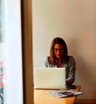 Mujer trabajando con una notebook junto a una ventana