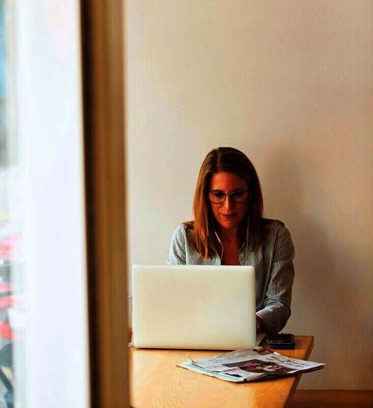 Mujer trabajando con una notebook junto a una ventana