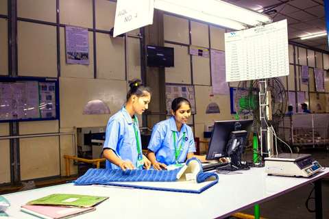 Dos operarias revisando una pieza textil en un puesto de control de calidad