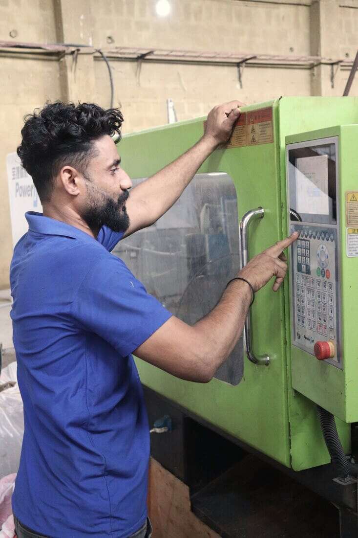 Operario apretando botones en el panel de una máquina industrial