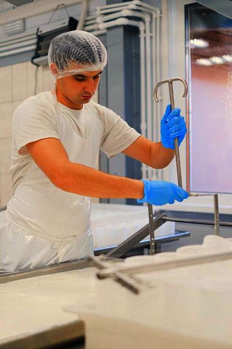 Operario con cofia y guantes trabajando en una planta de alimentos