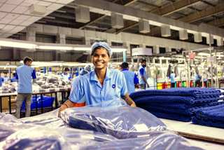 Operaria sonriendo con cofia y uniforme celeste en una planta textil