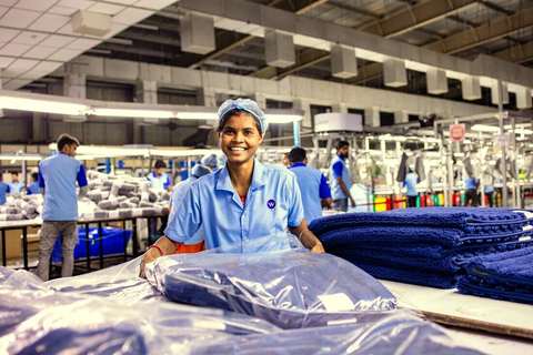 Operaria sonriendo con cofia y uniforme celeste en una planta textil