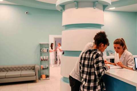 Dos personas consultando papeles en el mostrador de recepción de un centro médico