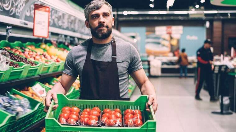 Empleado de supermercado con un cajón de tomates