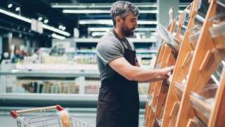 Empleado acomodando productos en un estante de supermercado